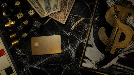 Luxury overhead flat-lay on black marble with scattered board-game tokens, dice, vintage play money, a gold credit card and t